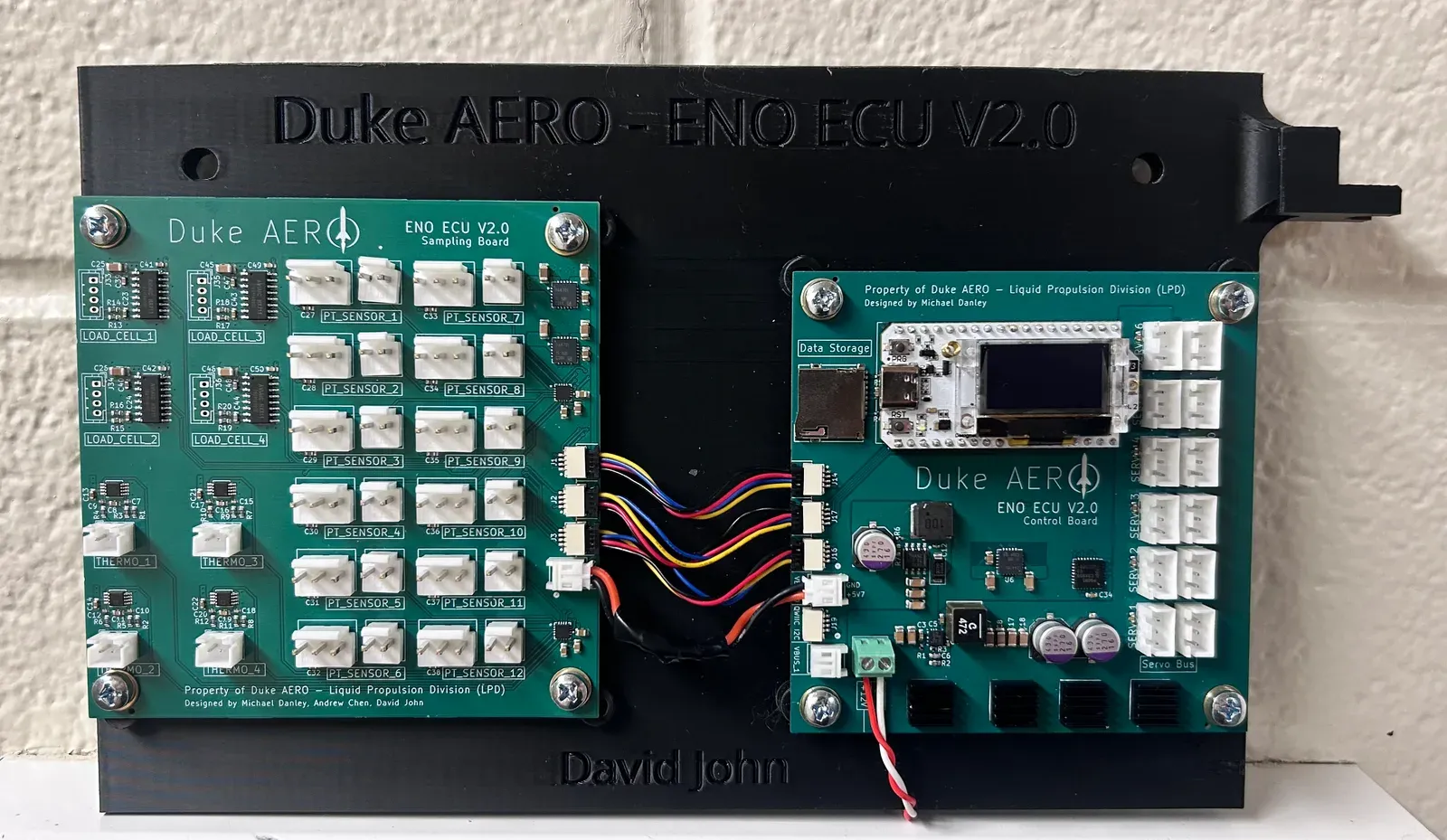 Two circuit boards mounted on a panel and connected with ribbon and power cables.