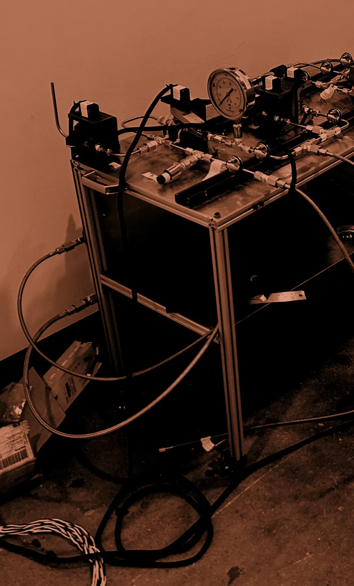 Duke AERO's liquid propulsion feed system: solenoid valves, a pressure gauge, and braided propellant lines on the test cart.