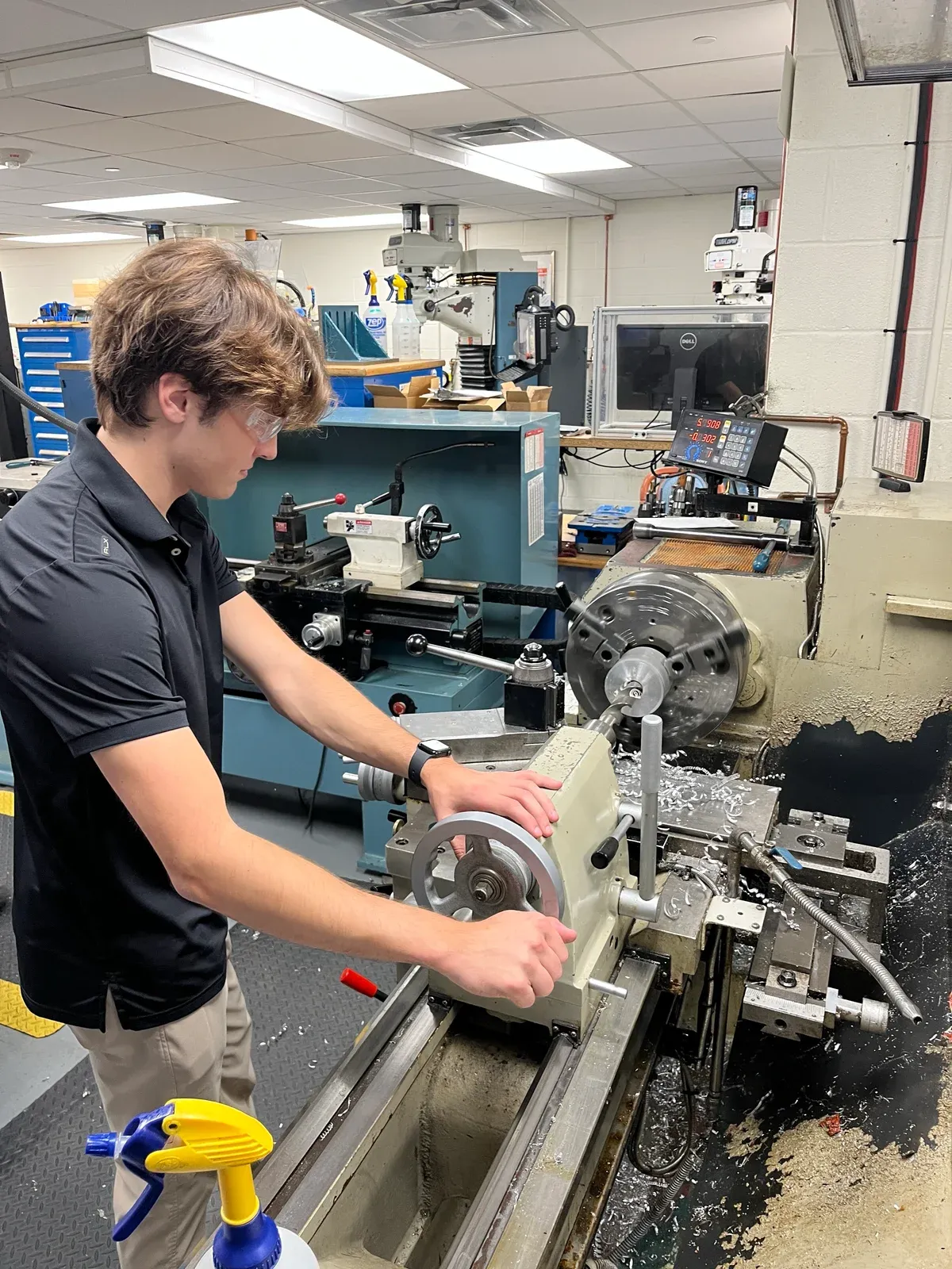 A student working at a lathe in the shared machine shop.