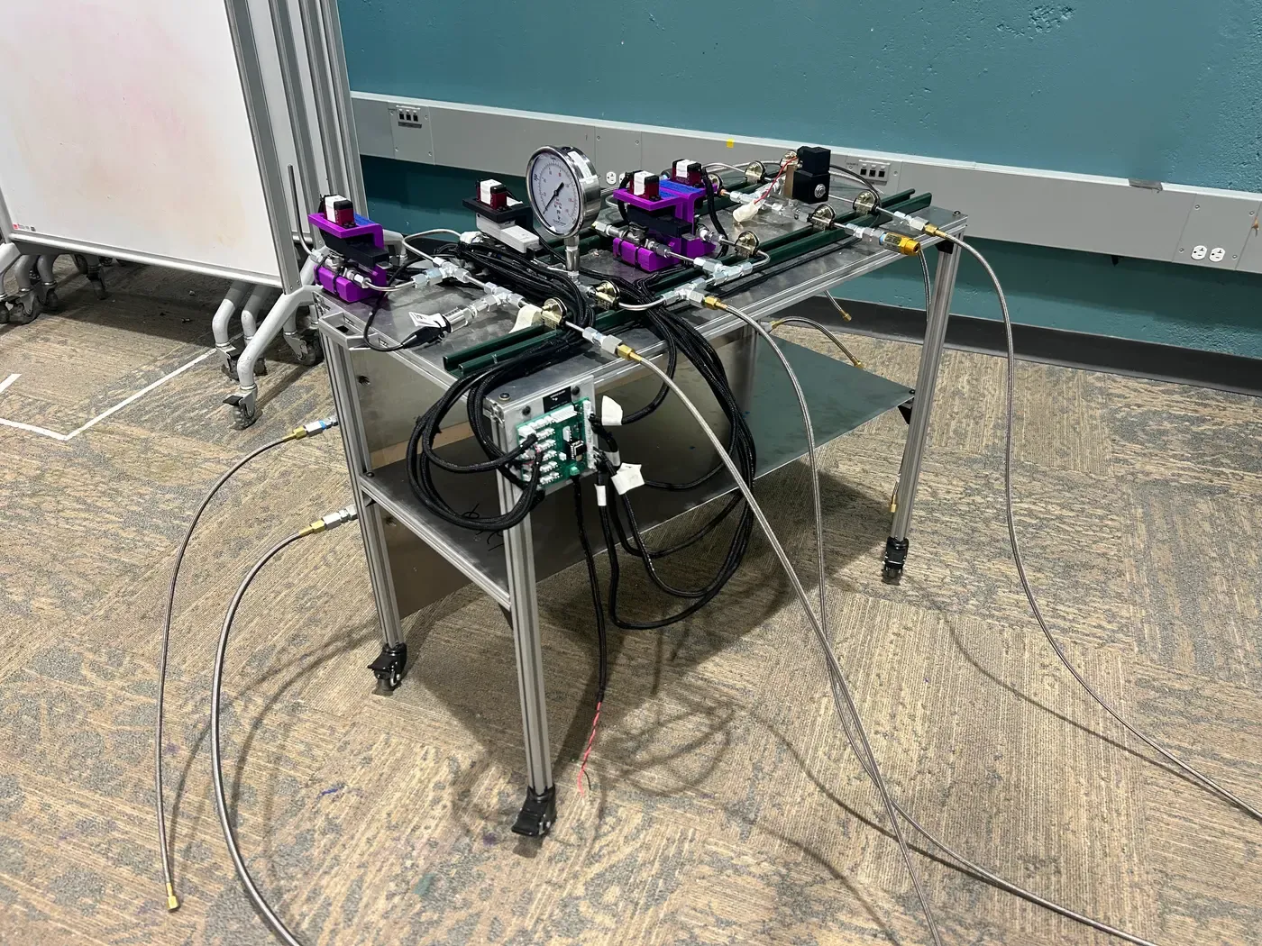 Propellant test platform with valves and a pressure gauge above the wired control electronics.